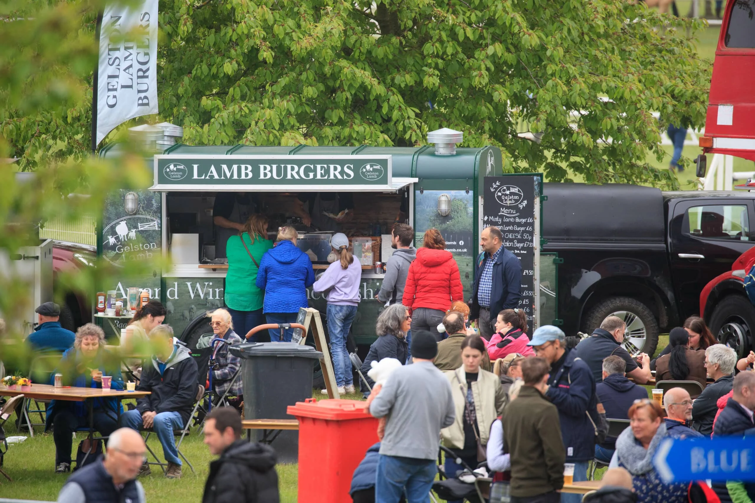 Customers queueing for food in crowded outdoor seating area