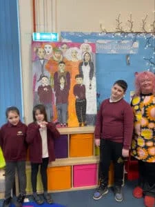 Three children from Dunston Primary and Nursery Academy pose with a canvas featuring Derbyshire heroes