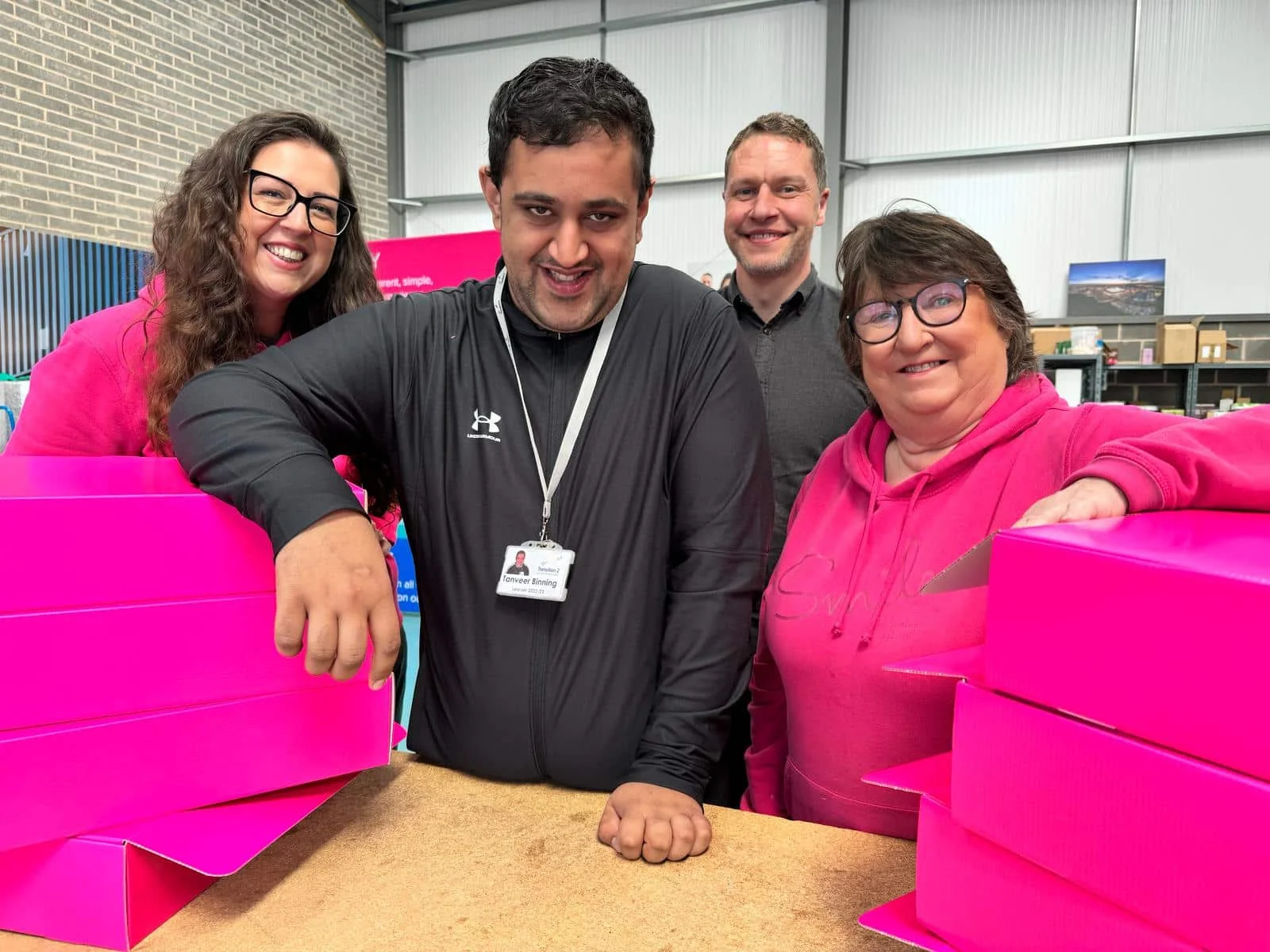 Four people stand in a row making up gift boxes