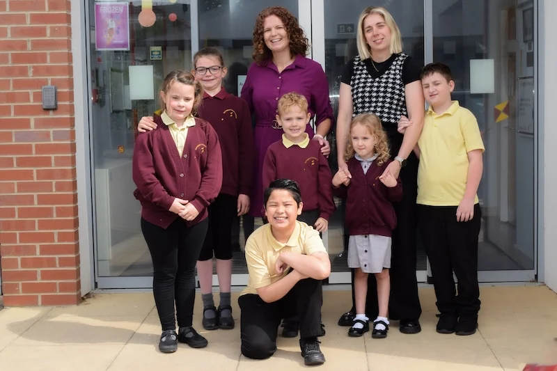 Children and teachers outside a school building