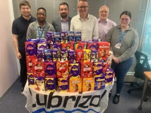 There are six members of Lubrizol’s team stood behind a Lubrizol branded table that is filled with Easter Eggs.