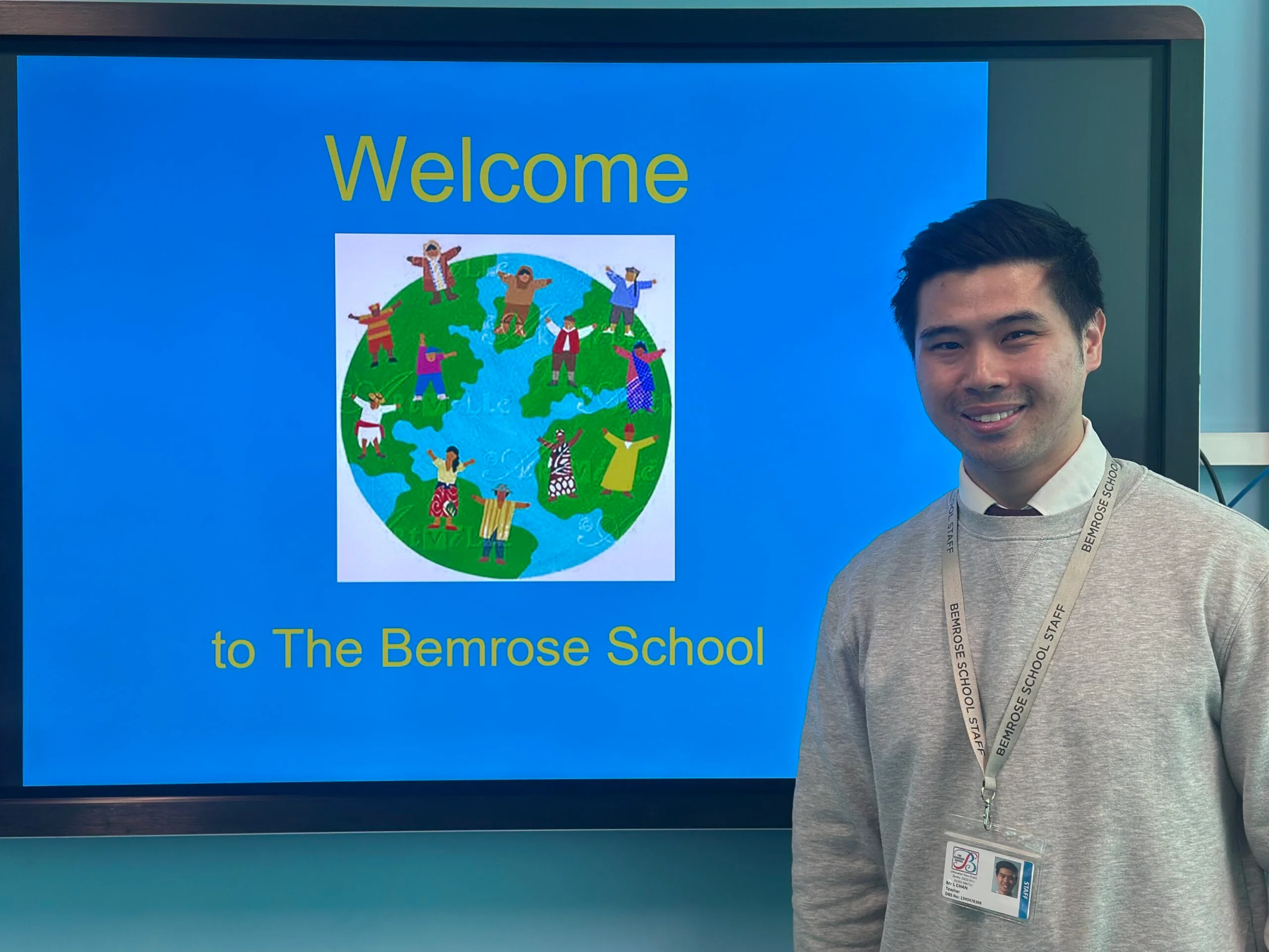 Leo Chan who is a teacher at Bemrose School standing infront of the interactive whiteboard that is depicting a logo