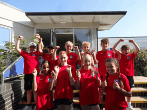 Students from Walter Evans Primary School posing in front of the entrance to the school celebrating their School Games Platinum Mark award