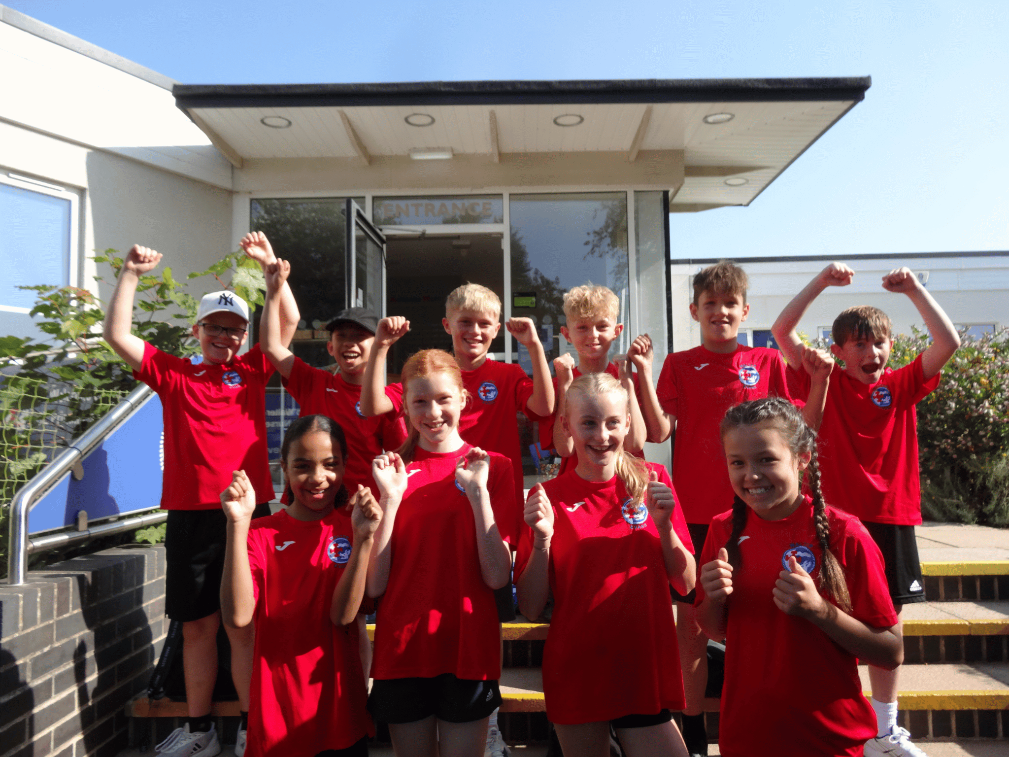 Students from Walter Evans Primary School posing in front of the entrance to the school celebrating their School Games Platinum Mark award